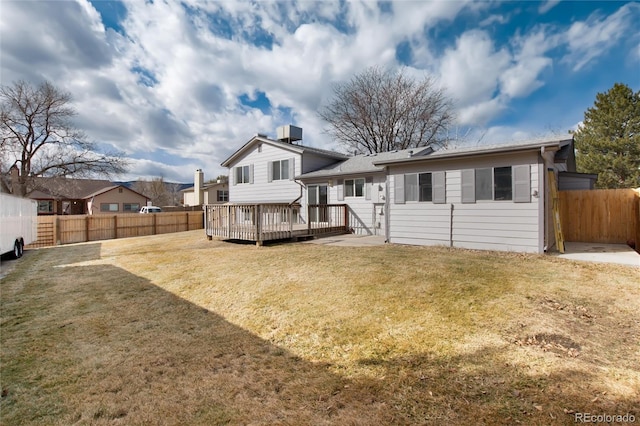 back of property with a deck and a lawn