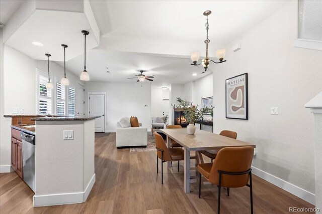 5850 Dripping Rock Ln Unit G102, Fort Collins, CO 80528 - dining area featuring wood finished floors, a chandelier, a ceiling fan, a warm lit fireplace, and baseboards