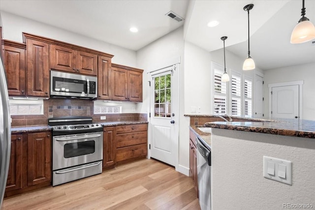 5850 Dripping Rock Ln Unit G102, Fort Collins, CO 80528 - kitchen featuring stainless steel appliances, light wood finished floors, dark stone countertops, decorative light fixtures, and decorative backsplash