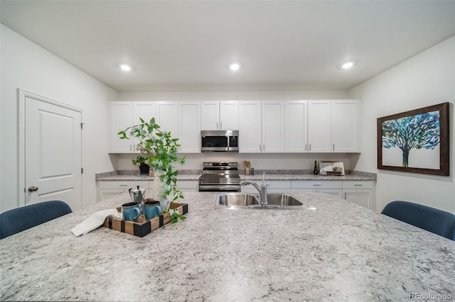 3899 N Shaenee St, Aurora, CO 80019 - kitchen with appliances with stainless steel finishes, a breakfast bar area, white cabinetry, light stone counters, and recessed lighting