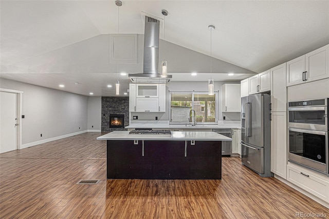 10051 E Walsh Pl, Denver, CO 80247 - kitchen featuring appliances with stainless steel finishes, vaulted ceiling, wall chimney range hood, a kitchen island, and dark wood finished floors