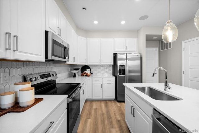 kitchen featuring a sink, light countertops, stainless steel appliances, light wood-type flooring, and backsplash
