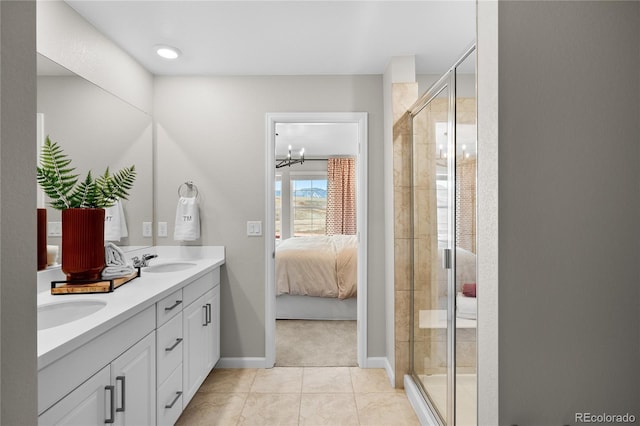 ensuite bathroom with double vanity, a stall shower, a sink, baseboards, and ensuite bath