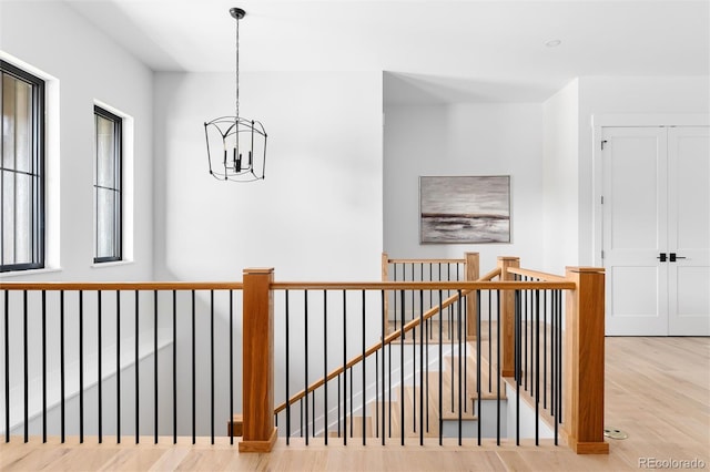 hall with light hardwood / wood-style floors and an inviting chandelier