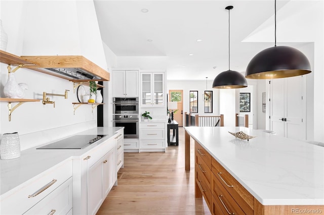 kitchen with light stone countertops, black electric stovetop, white cabinetry, hanging light fixtures, and stainless steel double oven