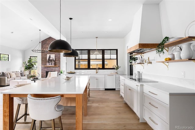 kitchen with black electric stovetop, white cabinetry, light wood-type flooring, sink, and a breakfast bar area