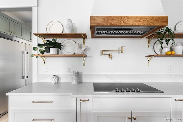 kitchen with built in refrigerator, white cabinetry, light stone countertops, and black electric cooktop