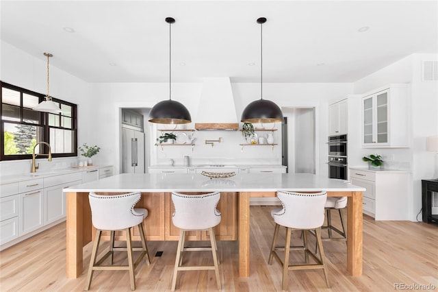 kitchen featuring white cabinetry, stainless steel appliances, a spacious island, and custom range hood