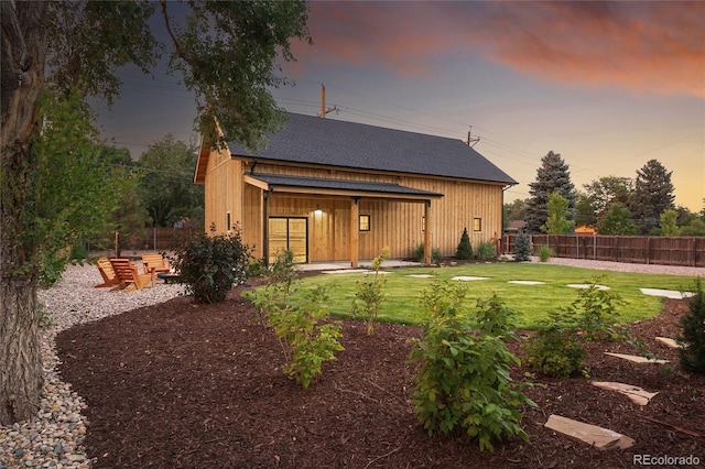 back house at dusk with a lawn