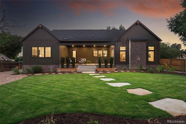 back house at dusk featuring a yard