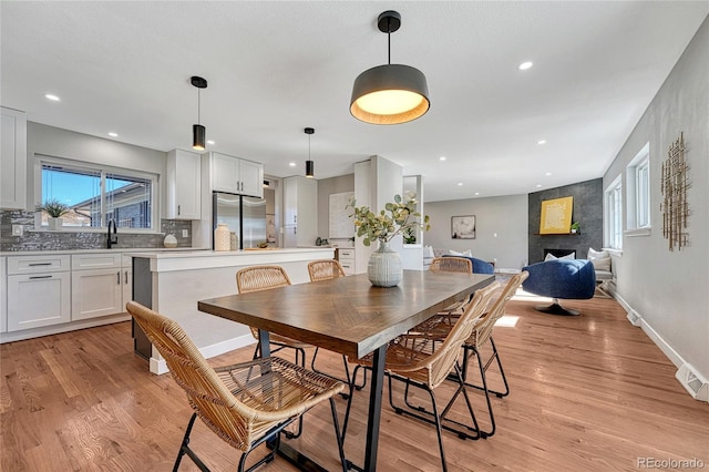 dining space with light wood-style flooring, plenty of natural light, a fireplace, and baseboards