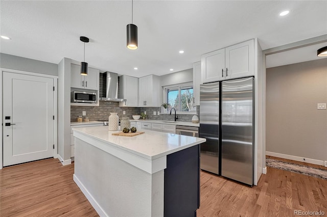 kitchen featuring tasteful backsplash, light wood-type flooring, stainless steel appliances, and wall chimney exhaust hood