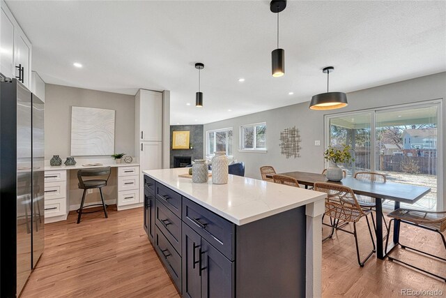 kitchen featuring white cabinetry, light wood finished floors, built in desk, and freestanding refrigerator