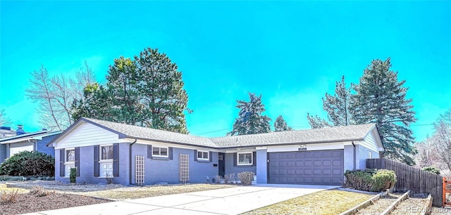 ranch-style house featuring a garage, brick siding, driveway, and fence