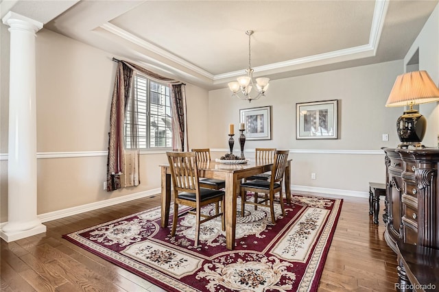 dining room with ornate columns, a tray ceiling, and hardwood / wood-style floors