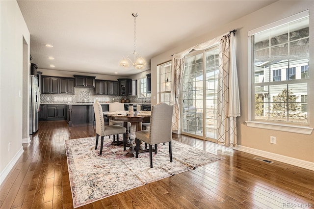 dining room featuring dark wood-style floors, a wealth of natural light, a chandelier, and baseboards