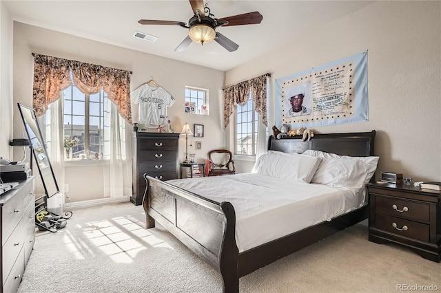 bedroom with a ceiling fan, visible vents, light carpet, and baseboards