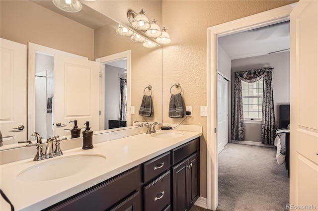 bathroom featuring double vanity, baseboards, a sink, and a textured wall