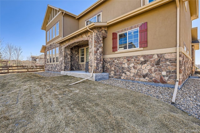 exterior space with stone siding, a patio, fence, and stucco siding