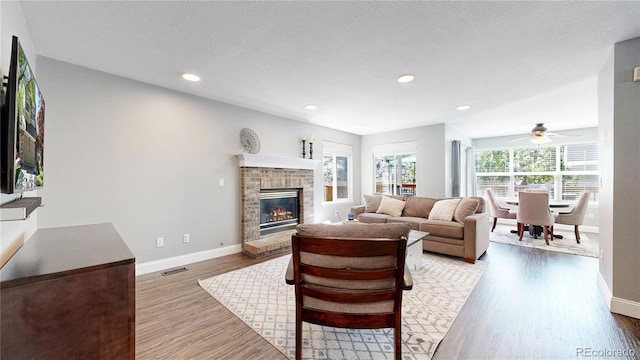 living area with wood finished floors, baseboards, a fireplace, and recessed lighting