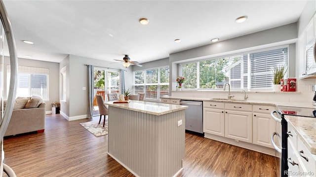 kitchen with appliances with stainless steel finishes, a sink, wood finished floors, light stone countertops, and recessed lighting