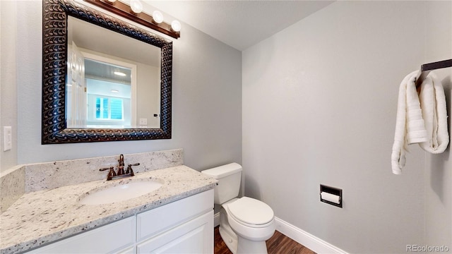 bathroom featuring wood finished floors, toilet, vanity, and baseboards