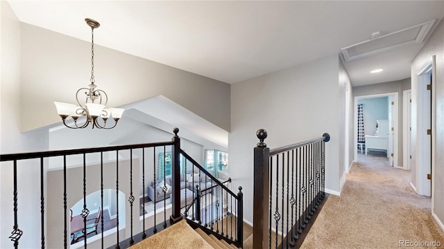 hall with a chandelier, an upstairs landing, carpet flooring, and baseboards