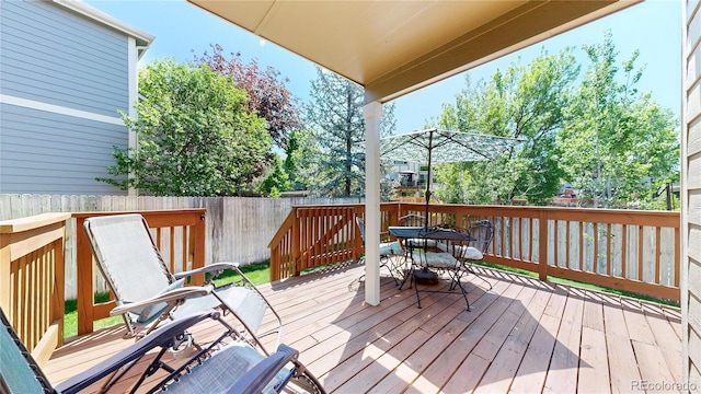 wooden terrace with outdoor dining space and fence