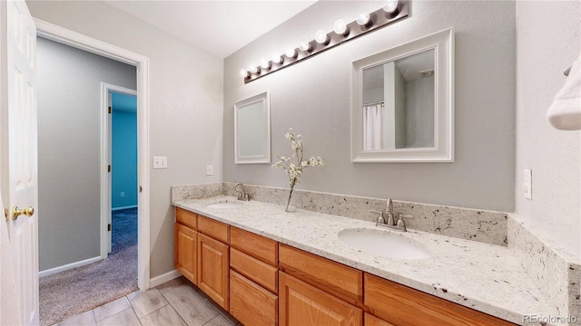 bathroom with double vanity, tile patterned floors, and baseboards