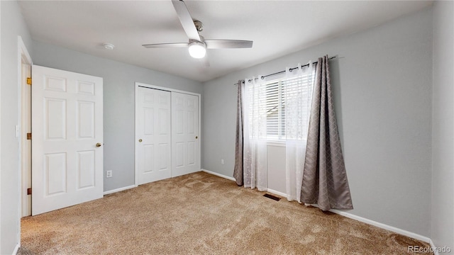 unfurnished bedroom featuring carpet flooring, a closet, baseboards, and a ceiling fan