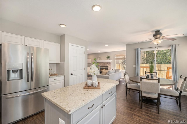 2980 E 135th Dr, Thornton, CO 80241 - kitchen featuring stainless steel fridge with ice dispenser, a brick fireplace, dark wood-style floors, a ceiling fan, and a center island