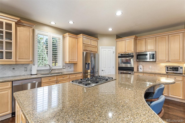 kitchen with light stone countertops, appliances with stainless steel finishes, light brown cabinets, and sink