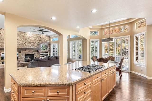 kitchen featuring ceiling fan, a center island, dark wood-type flooring, and stainless steel gas stovetop