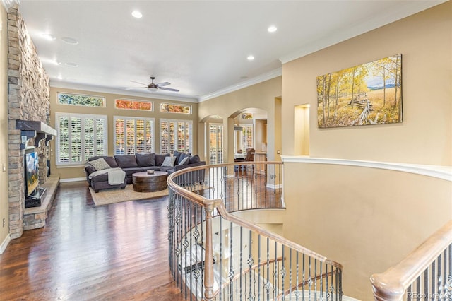 living room with a fireplace, ceiling fan, ornamental molding, and dark wood-type flooring