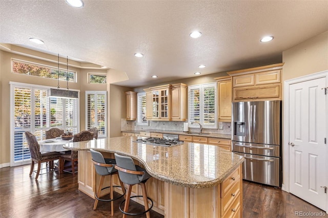 kitchen with appliances with stainless steel finishes, a textured ceiling, sink, dark hardwood / wood-style floors, and a kitchen island