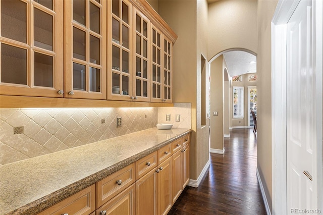 bar with dark hardwood / wood-style floors and backsplash