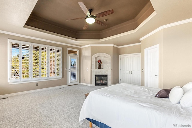 carpeted bedroom featuring a raised ceiling, ceiling fan, and crown molding