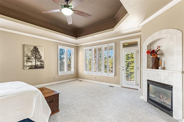 carpeted bedroom with access to outside, a tile fireplace, ceiling fan, and crown molding