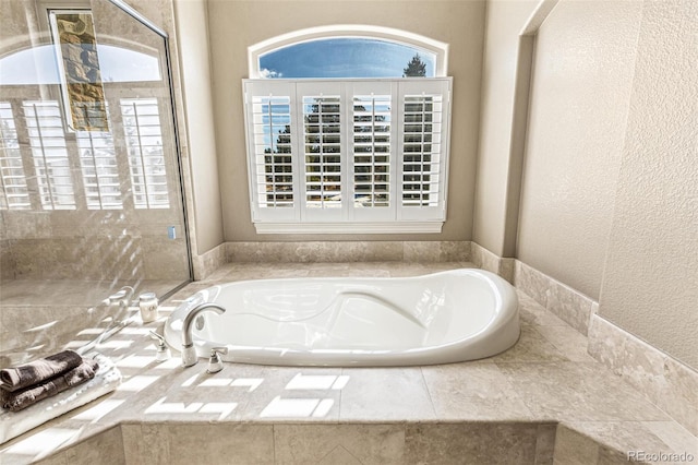 bathroom featuring plenty of natural light and tiled tub