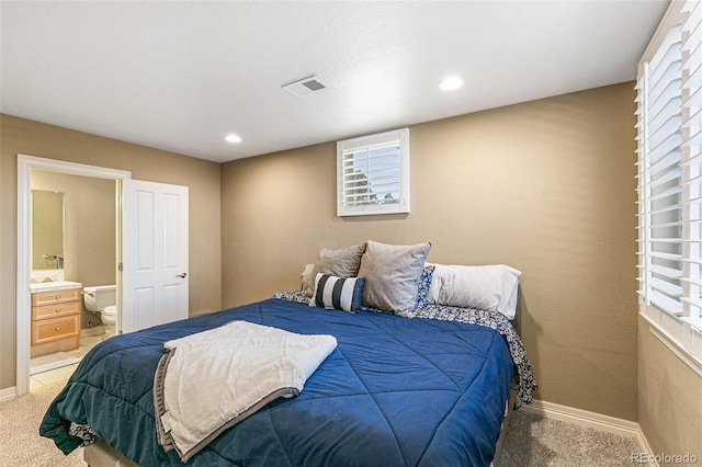 carpeted bedroom featuring ensuite bath