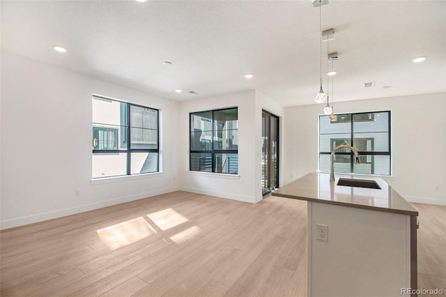 kitchen featuring a textured ceiling, sink, pendant lighting, and light hardwood / wood-style flooring