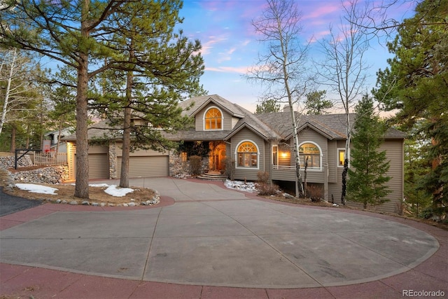 view of front of home with a garage, stone siding, and driveway