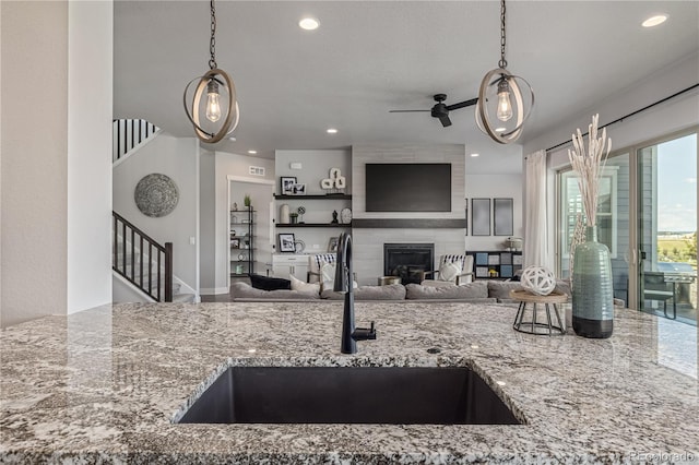 3256 Offbeaten Pl, Castle Rock, CO 80108 - kitchen with light stone counters, open floor plan, hanging light fixtures, recessed lighting, and a fireplace