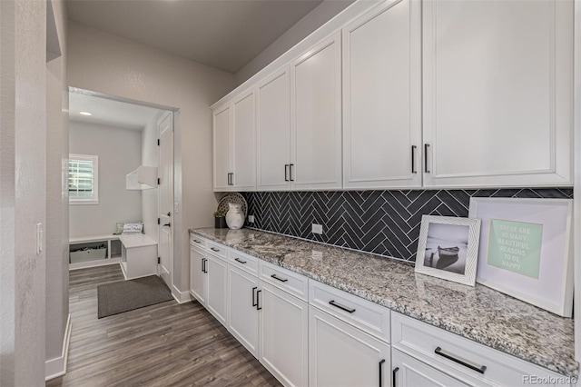 3256 Offbeaten Pl, Castle Rock, CO 80108 - kitchen featuring white cabinets, dark wood-type flooring, backsplash, and light stone counters