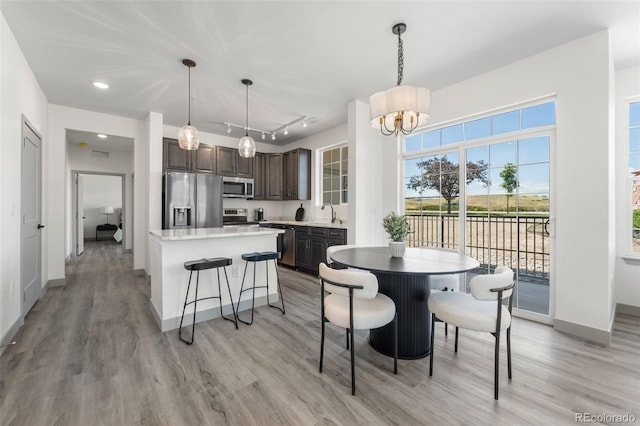 dining room with sink, rail lighting, a chandelier, and light wood-type flooring