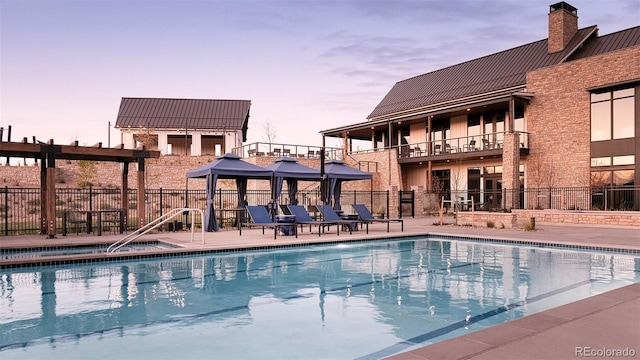 pool at dusk with a patio area