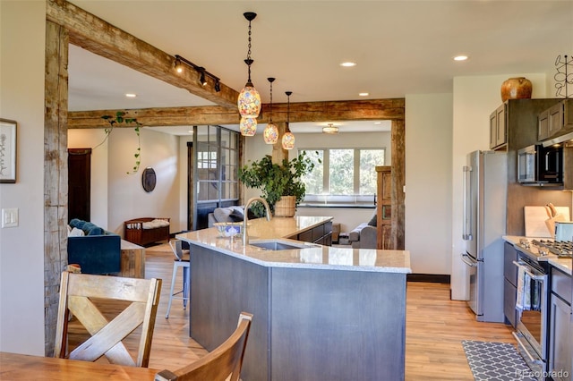 104 River Run Dr, Buena Vista, CO 81211 - kitchen featuring stainless steel appliances, open floor plan, light wood-style flooring, a kitchen breakfast bar, and light stone counters
