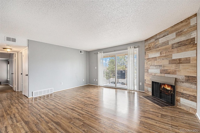 unfurnished living room featuring visible vents, a fireplace, and wood finished floors