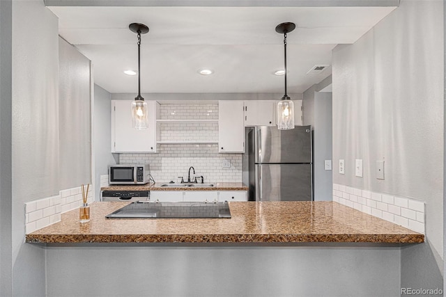 kitchen featuring backsplash, appliances with stainless steel finishes, a peninsula, white cabinets, and a sink