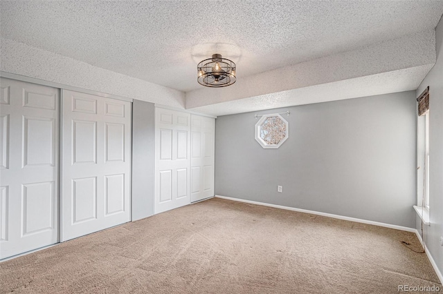 unfurnished bedroom featuring baseboards, carpet floors, a textured ceiling, and a closet